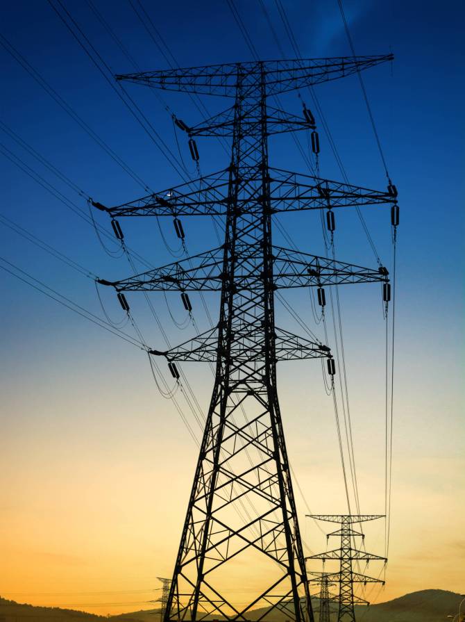 Sun setting behind the silhouette of electricity pylons